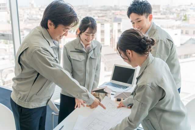 設計図を囲んで話し合う建設チーム